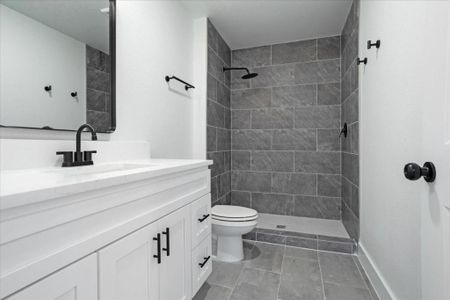 Bathroom featuring vanity, toilet, tile patterned floors, and a tile shower