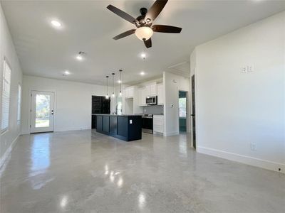 Kitchen with stainless steel appliances, white cabinetry, ceiling fan, an island with sink, and pendant lighting