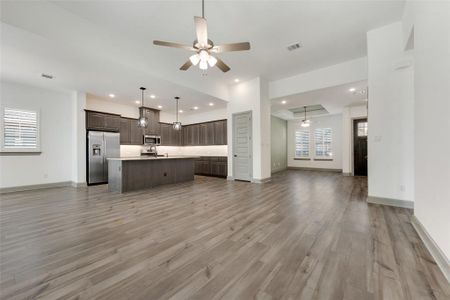 Kitchen featuring light wood-type flooring, stainless steel appliances, a center island with sink, a healthy amount of sunlight, and ceiling fan