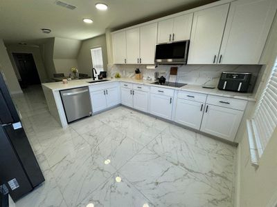 Kitchen with stainless steel appliances, kitchen peninsula, white cabinets, and sink