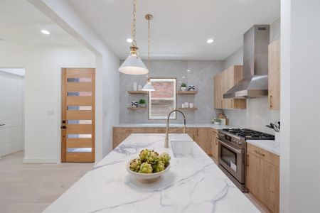 Upon entering through this modern glass and white oak door, you are greeted by a designer kitchen.