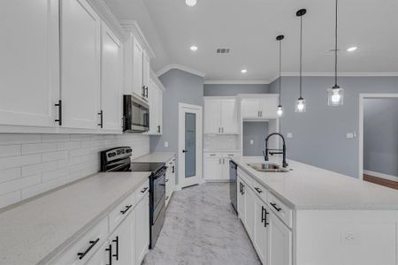 Kitchen featuring tasteful backsplash, a center island with sink, pendant lighting, sink, and appliances with stainless steel finishes