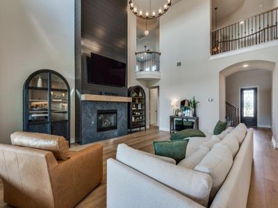 Living room with a high ceiling, light wood-type flooring, and a fireplace