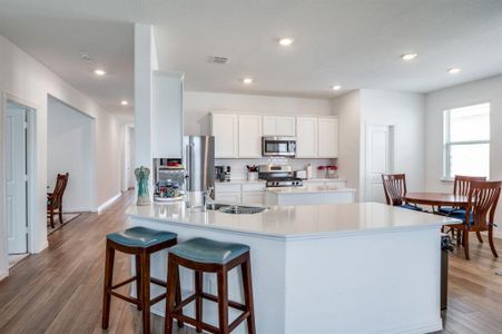 Kitchen with appliances with stainless steel finishes, light hardwood / wood-style floors, white cabinetry, and sink