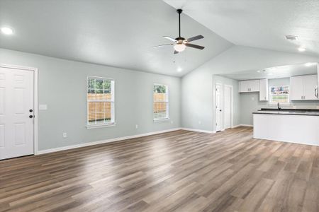 Unfurnished living room featuring vaulted ceiling, ceiling fan, and hardwood / wood-style flooring