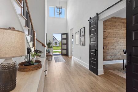 Study with custom wall installation and modern black barn doors adjacent to foyer