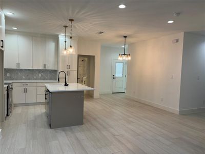 Kitchen featuring decorative light fixtures, sink, stainless steel range with electric cooktop, and an island with sink