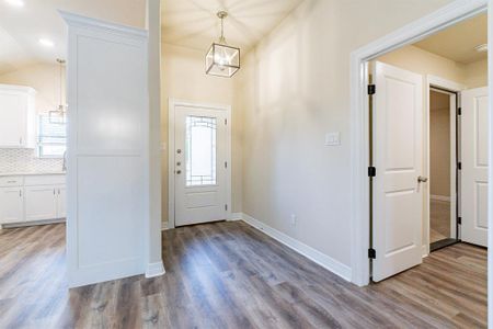 Entryway with a wealth of natural light, lofted ceiling, and light hardwood / wood-style floors, decorative lighting