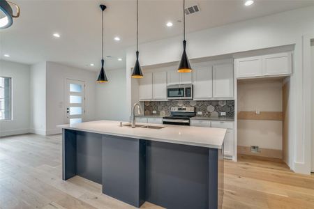Kitchen featuring light hardwood / wood-style floors, a center island with sink, appliances with stainless steel finishes, white cabinets, and sink