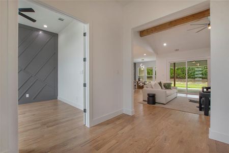 Corridor with vaulted ceiling with beams and light wood-type flooring