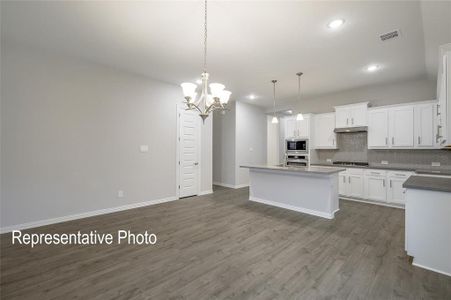 Kitchen featuring appliances with stainless steel finishes, white cabinetry, a center island, and dark hardwood / wood-style floors