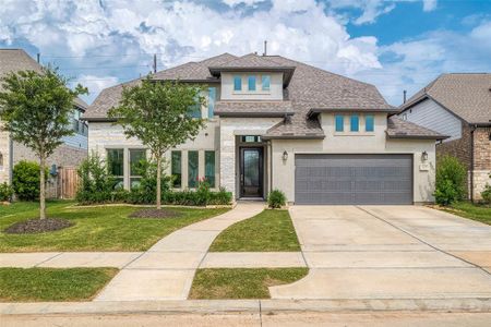 Modern two-story home with a stone and stucco exterior, featuring a two-car garage and well-maintained landscaping.