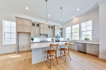 Bright and light chef's kitchen with huge island, white marble backsplash, and unobstructed green views