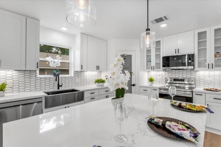 Kitchen featuring white cabinets, sink, backsplash, and stainless steel appliances