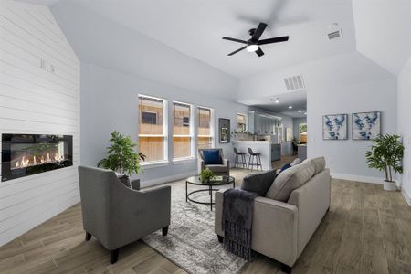 Living room with ceiling fan, hardwood / wood-style floors, high vaulted ceiling, and a large fireplace