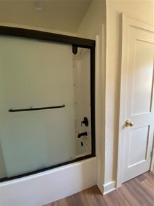 Bathroom with shower / bath combination with glass door and hardwood / wood-style floors