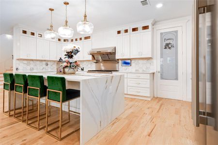 Kitchen featuring a kitchen island, light hardwood / wood-style flooring, white cabinets, and tasteful backsplash