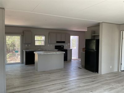 Kitchen with black appliances, a kitchen island, gray cabinets, and a wealth of natural light