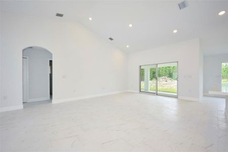 Great room with sliders that lead out to under-truss lanai area.  Doorway to left in picture lead to secondary bedrooms and guest bath.