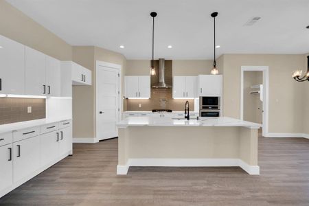 Kitchen featuring white cabinets, an island with sink, tasteful backsplash, light hardwood / wood-style flooring, and wall chimney range hood