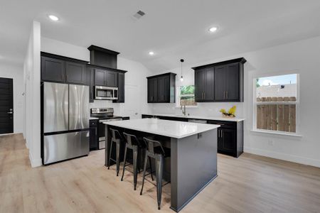 Kitchen with a center island, light hardwood / wood-style flooring, appliances with stainless steel finishes, backsplash, and sink