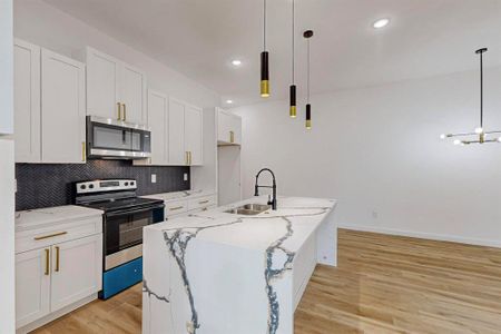 Kitchen with white cabinets, appliances with stainless steel finishes, hanging light fixtures, and sink