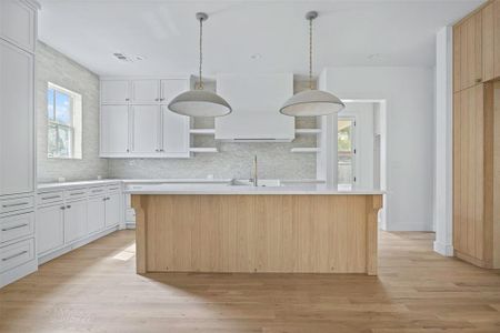 Kitchen with a healthy amount of sunlight, white cabinets, and a kitchen island with sink