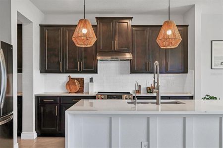 Waterfall edge quartz island with a custom finish is a showpiece in this beautifully updated kitchen with brass hardware, subway tile backsplash. and new range with hood!