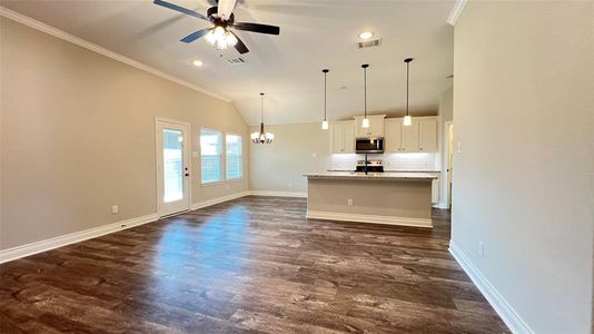 Kitchen with pendant lighting, dark hardwood / wood-style floors, white cabinetry, stainless steel appliances, and a center island with sink