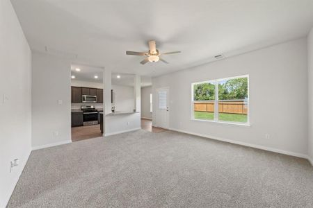 Unfurnished living room with light carpet and ceiling fan