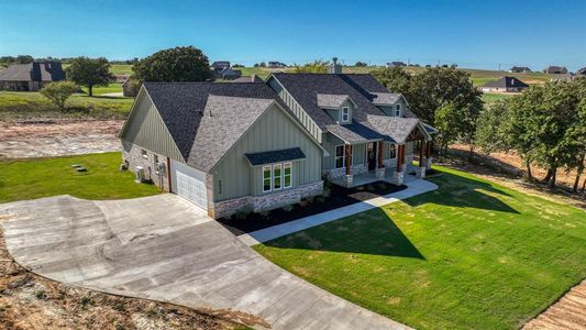 View of front of house with a front lawn, covered porch, and 2-car garage