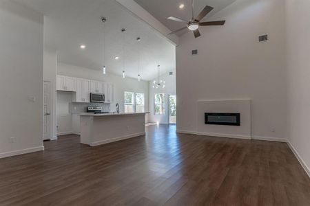 Open concept layout with electric fireplace, high ceilings and modern lighting