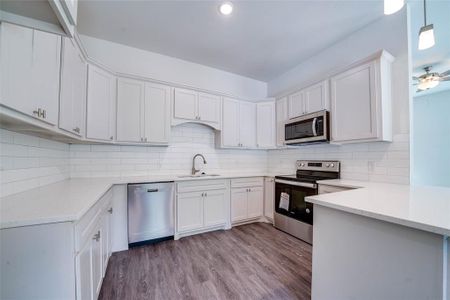 Kitchen with sink, wood-type flooring, tasteful backsplash, and stainless steel appliances