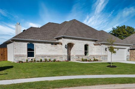 French country inspired facade with a garage and a front lawn