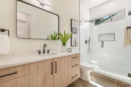 Bathroom featuring vanity, toilet, tile patterned floors, and walk in shower