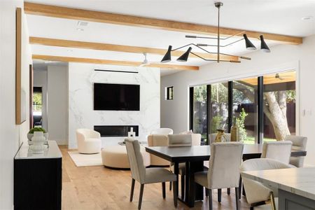 Dining space featuring an inviting chandelier, light hardwood / wood-style floors, beamed ceiling, and a fireplace