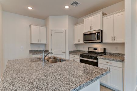 The Olive floorplans kitchen featuring white cabinets and speckled countertops.