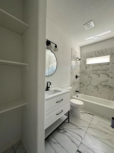 Full bathroom with tile flooring, vanity, toilet, and tiled shower / bath combo