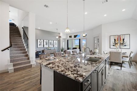 Kitchen with decorative light fixtures, a center island with sink, sink, hardwood / wood-style flooring, and ceiling fan