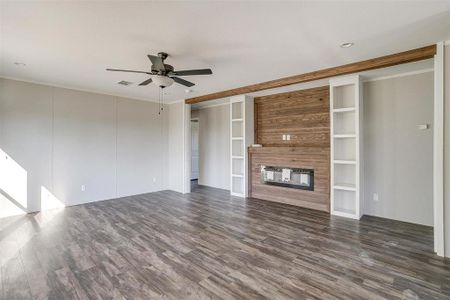 Unfurnished living room with crown molding, ceiling fan, dark hardwood / wood-style flooring, and a multi sided fireplace