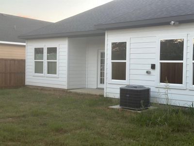 Back house at dusk featuring a lawn and central AC