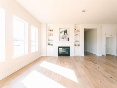 Unfurnished living room with a high end fireplace and light hardwood / wood-style floors