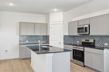 Kitchen with stainless steel appliances, gray cabinets, backsplash, and light hardwood / wood-style floors