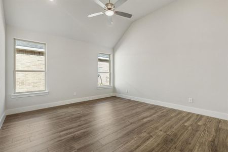 Unfurnished room featuring dark hardwood / wood-style floors, ceiling fan, lofted ceiling, and a healthy amount of sunlight