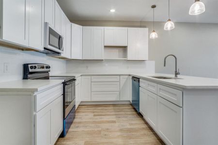 Kitchen featuring tasteful backsplash, stainless steel appliances, light hardwood / wood-style floors, decorative light fixtures, and sink