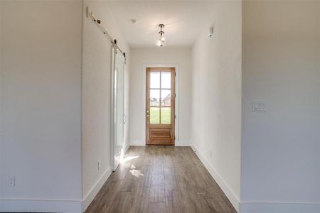 Entryway with a barn door and wood-type flooring