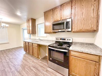 Kitchen featuring light wood-type flooring, sink, a chandelier, and stainless steel appliances