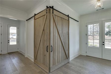 Entrance foyer featuring a healthy amount of sunlight, a barn door, light hardwood / wood-style floors, and a chandelier