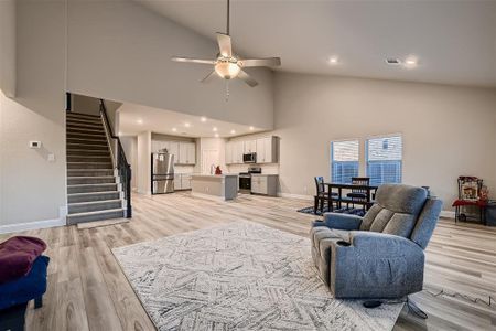 Living room featuring light hardwood / wood-style floors, sink, high vaulted ceiling, and ceiling fan