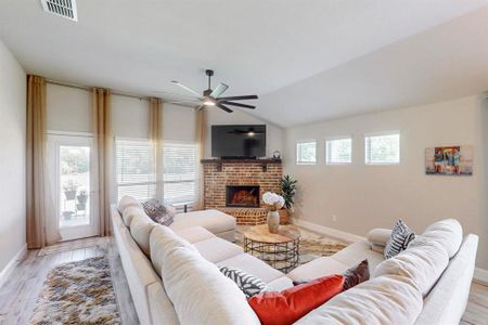 Living room featuring ceiling fan, a fireplace, light wood-type flooring, and plenty of natural light